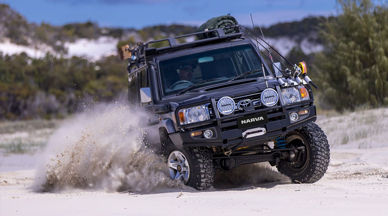 Toyota Landcruiser with Narva Ultima driving MK2 lights spraying sand on the beach