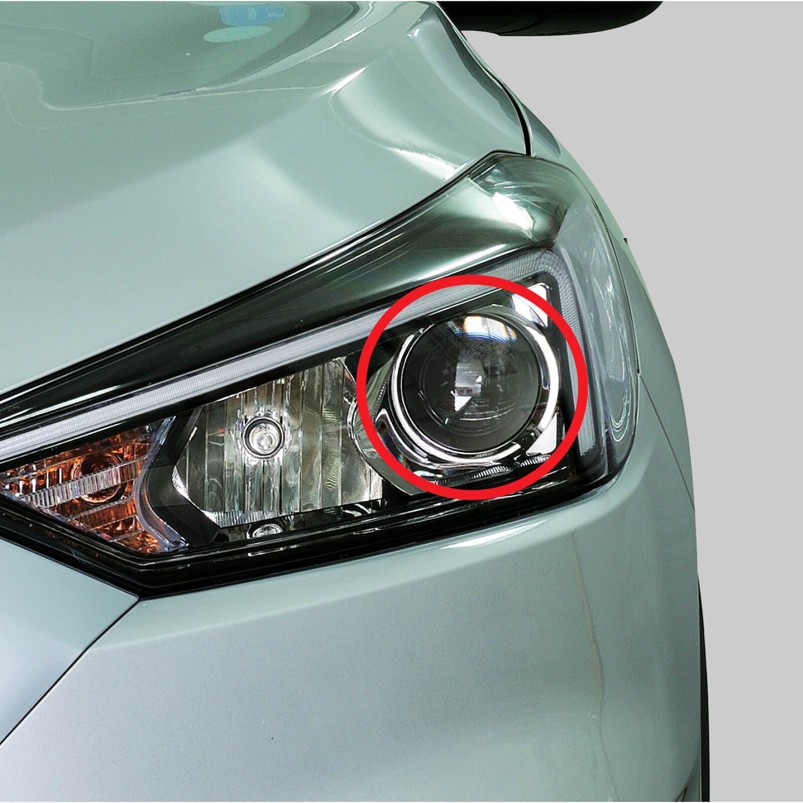 A close up of a projector style headlight on a white car